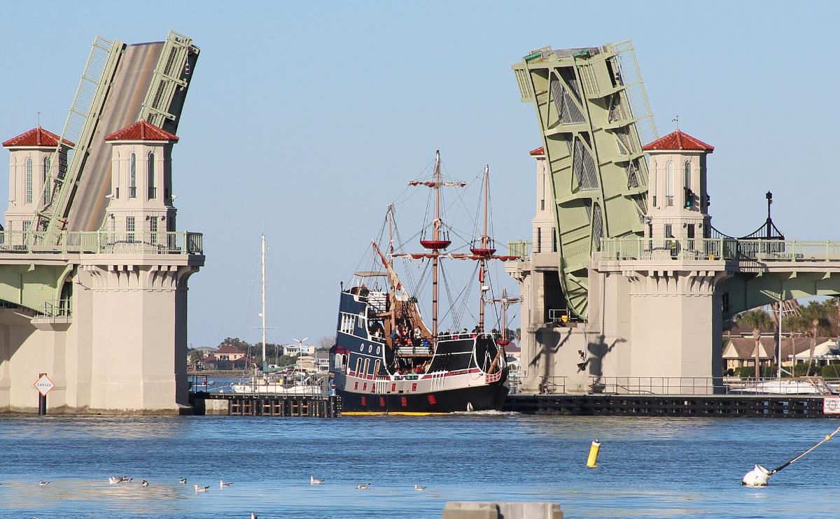 Gary Leavens, CC BY-SA 2.0 A replica pirate ship sailing through the open Bridge of Lions